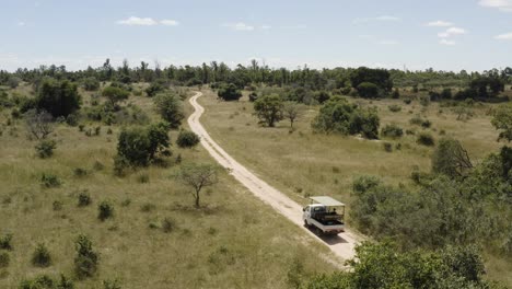 Aerial-static-shot-of-a-safari-car-driving-down-a-road-during-daytime-at-Imire-Zimbabwe