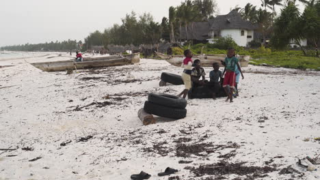 Afrikanische-Kinder-Machen-Saltos-Aus-Gestapelten-Reifen-Am-Strand-Von-Sansibar