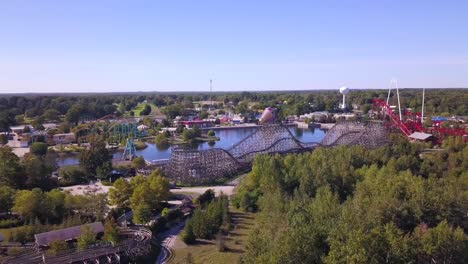 Forward-aerial-of-rollercoasters-at-amusement-park-on-clear-sunny-day