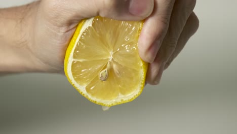 Squeezing-lemon-juice-from-juicy-fresh-cut-lemon-with-yellow-peel-and-white-rind-in-slow-motion