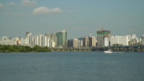 Motorjachtboot,-Das-Auf-Dem-Hangang-Fluss-In-Richtung-Der-Insel-Bamseom-Mit-Der-Skyline-Der-Stadt-Seoul-Kreuzt-–-Autoverkehr-Auf-Der-Gangbyeon-Schnellstraße,-Mapodaegyo-Mapo-Brücke,-Seoul-Namsan-Turm