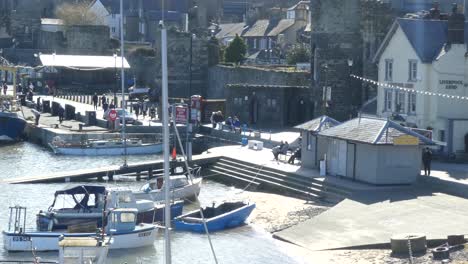 Scenic-Welsh-coastal-fishing-market-castle-town-harbour,-sailboats-anchored-on-waterfront