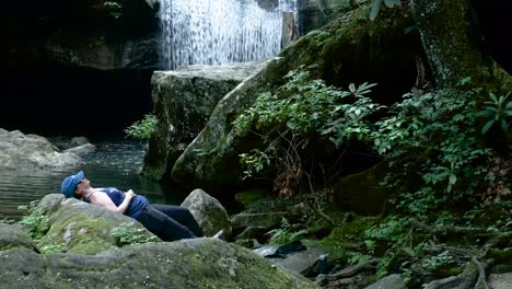 Female-Hiker-Relaxing-Near-a-Beautiful-Waterfall