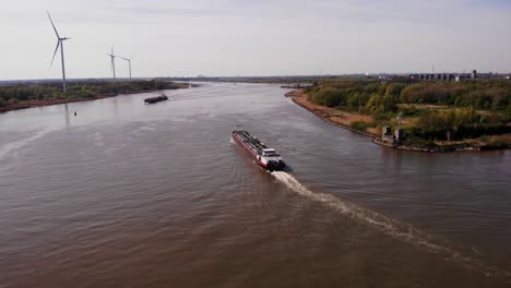 Aerial-View-Of-Da-Vinci-Motor-Tanker-Ship-Navigating-Along-Oude-Maas-With-Row-Of-Wind-Turbines-Seen-In-Background
