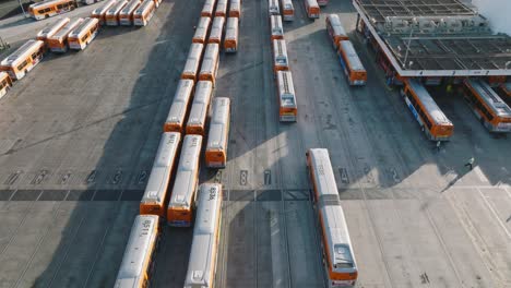 Autobuses-De-La-Metro-Estacionados-En-La-Estación,-Drones-Aéreos-Volando-Sobre-Autobuses-Naranjas