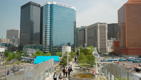 Groups-of-people-in-masks-walking-along-Seoullo-7017-skygarden-park-above-Seoul's-city-streets