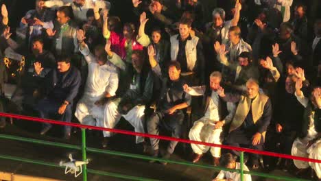 High-Angle-View-Of-PTI-Party-With-Imran-Khan-Sitting-Down-With-Arm-In-Air-At-Rally-In-Karachi