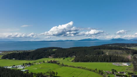 Aerial-shot-of-Whidbey-Island's-farm-land-with-the-San-Juans-off-in-the-distance