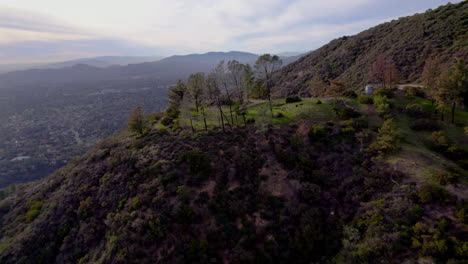 A-drone-shot-pushing-in-on-a-clearing-on-an-overlook-at-the-top-of-a-mountain-at-golden-hour