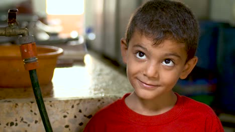 A-young-boy-in-Gaza-looking-at-the-camera-and-up-with-big-innocent-eyes-inside-a-kitchen