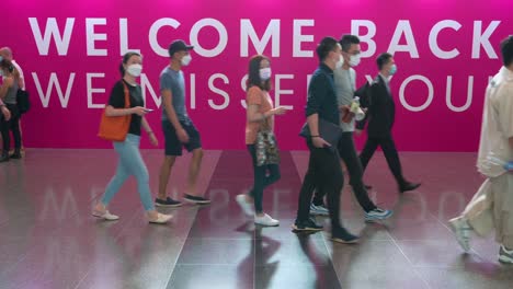 Art-buyers-walk-past-a-large-banner-with-the-message-"Welcome-Back,-We-Miss-you"-as-they-arrive-at-a-contemporary-art-fair-open-to-the-public