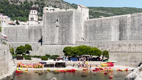 Dubrovnik-old-town-walls-on-a-summer-day-with-sea-kayaks,-Dubrovnik,-Croatia