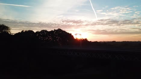 Horizontal-panning-aerial-shot-of-rail-bridge-at-sunset