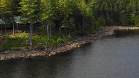 Luftaufnahmen-Eines-Abgelegenen-Sees-Im-Norden-Von-Maine,-Der-Herauszoomt,-Während-Er-Nach-Rechts-An-Einem-Lager-Vorbeigleitet