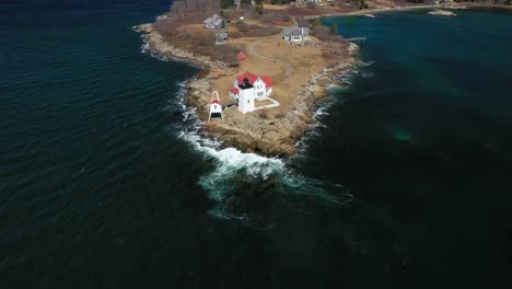 Stationary-aerial-shot-of-waves-crashing-onto-the-rocky-shore-by-Hendricks-Head-Lighthouse