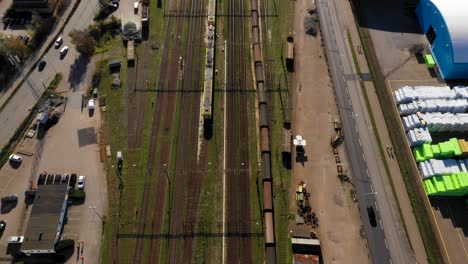 Aerial-view-of-train-tracks-going-alongside-industry-harbour-towards-city