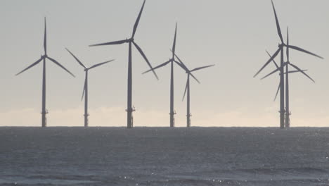 Wind-turbines-spinning-at-an-offshore-farm-off-the-coast-of-Hartlepool-in-the-North-Sea-as-waves-crash-on-the-shore