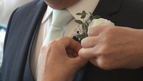 Person-attaches-boutonnière-to-wedding-guests-suit