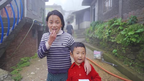 Poor-Asian-brother-and-sister-smiling-and-looking-at-camera-at-foggy-morning-in-winter,-slow-motion