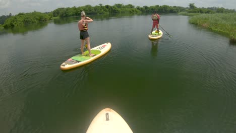A-point-of-view-shot-from-the-perspective-of-a-man-paddling-on-a-stand-up-paddle-board-on-the-river-Nile-with-other-stand-up-paddlers