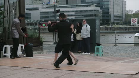 FOLLOW-MEDIUM-SHOT-Skilled-tango-dancers-couple-dancing-for-tip-on-Puerto-Madero