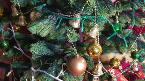 Primer-Plano-De-Un-árbol-De-Navidad-De-Plástico-Completamente-Decorado-Con-Bolas-De-Navidad,-Campanas,-Tarjetas-Y-Luz-De-Navidad