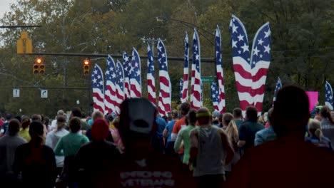 Columbus-Ohio-Marathon-2019-runners-moving-away-running-west-on-Broad-Street-in-slow-motion-with-American-flags-in-background