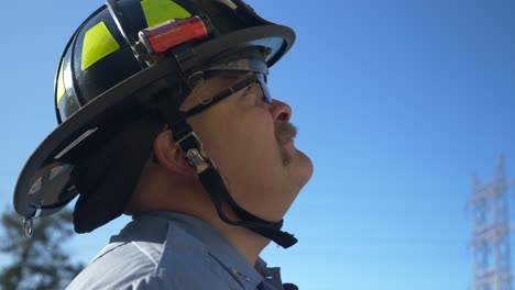 Ein-Feuerwehrmann-Blickt-In-Die-Luft-Und-Betrachtet-Eine-Leiter,-Die-Er-Auf-Einem-Feuerwehrauto-Steuert