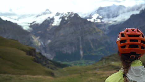 Woman-mountain-biker-gazing-at-the-snow-topped-Swiss-alps