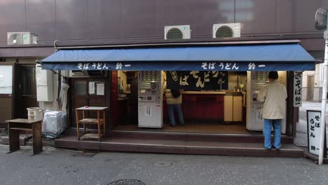 Front-View-Of-A-Street-Food-Stall-At-The-Back-Of-A-Building-In-Tokyo-Japan-With-Customers-Buying---Wide-Shot