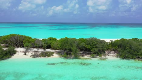 Lush-vegetation-of-tropical-island-thriving-over-white-sand-washed-by-turquoise-lagoon-with-coral-reef-on-a-hot-summer-day-in-Seychelles