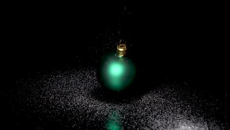 Crystalline-snow-trickles-gently-on-isolated-green-Christmas-ball-on-a-black-surface