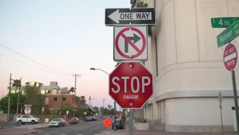Stop-sign-at-intersection-with-sticker-that-says-racism-on-it-on-a-windy-day-in-Las-Vegas,-Nevada