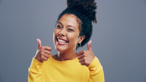 a-young-woman-showing-thumbs-up-against-a-grey
