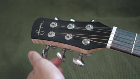 Loosening-The-Strings-Of-An-Acoustic-Guitar-By-Tuning-The-Machine-Heads---close-up