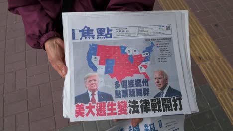 Eine-Frau-Verteilt-Eine-Chinesischsprachige-Zeitung,-Auf-Deren-Titelseite-Das-US-Präsidentschaftsrennen-Zwischen-Dem-Derzeitigen-Präsidenten-Donald-J.-Und-Donald-J.-Zu-Sehen-Ist