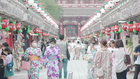 Japanese-Girls-In-Kimono-Wearing-Masks-At-The-Nakamise-Shopping-Street-During-Coronavirus-Crisis-In-Asakusa,-Tokyo,-Japan---long-shot