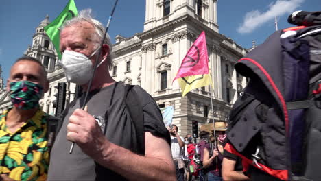 An-Einem-Sonnigen-Tag-Marschieren-Demonstranten-Der-Rebellion-Gegen-Den-Klimawandel-Mit-Schutzmasken-Aufgrund-Der-Coronavirus-Pandemie-Und-Verschiedenen-Bunten-Plakaten-Und-Bannern-Durch-London