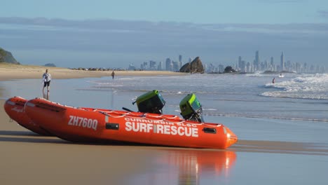 Inflatable-Rescue-Boats-On-The-Sandy-Beach---Gold-Coast-Skyline-In-The-Distance-From-Currumbin-Beach---Surfing-Paradise-In-Queensland,-Australia