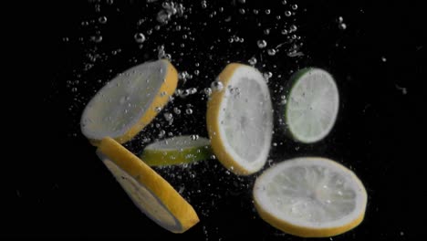 Lemon-Slices-Falling-into-Water-Super-Slowmotion,-Black-Background,-lots-of-Air-Bubbles,-4k240fps