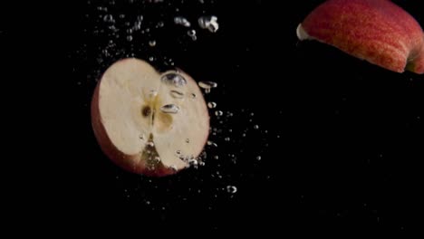Apfel-Fällt-Ins-Wasser-Super-Slowmotion,-Schwarzer-Hintergrund,-Viele-Luftblasen,-4k240fps