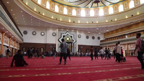 Muslimische-Menschen-Gehen-Auf-Teppichboden-In-Der-Islamischen-Zentrumsmoschee-In-Mataram,-Lombok-Mit-Eleganter-Decke-–-Niedrige-Ebene,-Weitwinkelaufnahme