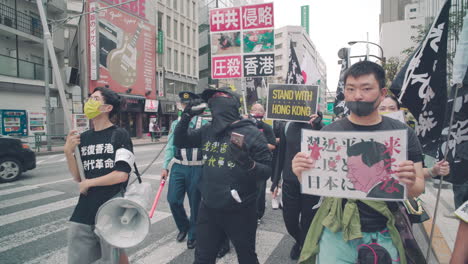 Protesters-In-The-Street-Of-Tokyo-Holding-Stand-With-Hong-Kong-Placard-And-Anti-CCP-Banners---medium-shot