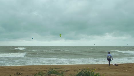 Kite-surfing-surfers-sailing-on-the-big-Baltic-sea-waves-at-Liepaja-Karosta-beach,-overcast-autumn-day,-wide-shot