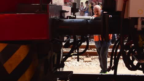 Train-engine-connects-to-rolling-stock-and-Bulgarian-railway-worker-wearing-orange-hi-vis-safety-workwear,moves-between-train-engine-and-carriages-to-couple-them-together