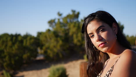 A-beautiful-hispanic-woman-modeling-and-posing-with-serious-staring-eyes-outdoors-in-a-desert-nature-landscape-at-sunset