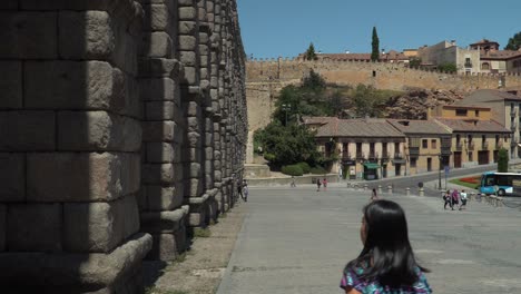 Locked-off-static-view-of-Segovia-aqueduct-with-tourists-standing-in-front-of-it
