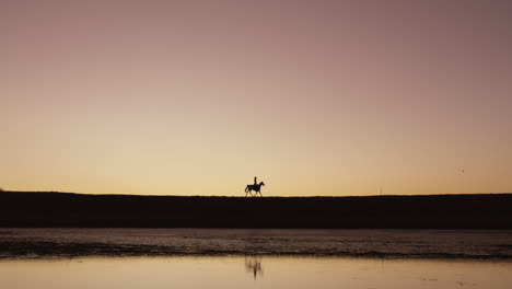 a-silhouetted-woman-riding-a-horse-on-a-ranch
