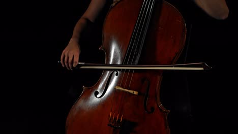Closeup-of-female-hands-playing-cello,-black-moody-background