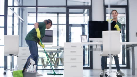 two-young-women-dancing-while-cleaning-an-office